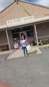 Woman standing outside a factory sales shop front with two bags